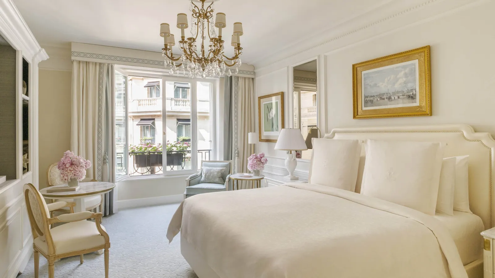 A bedroom with a bed, chandelier and sitting area
