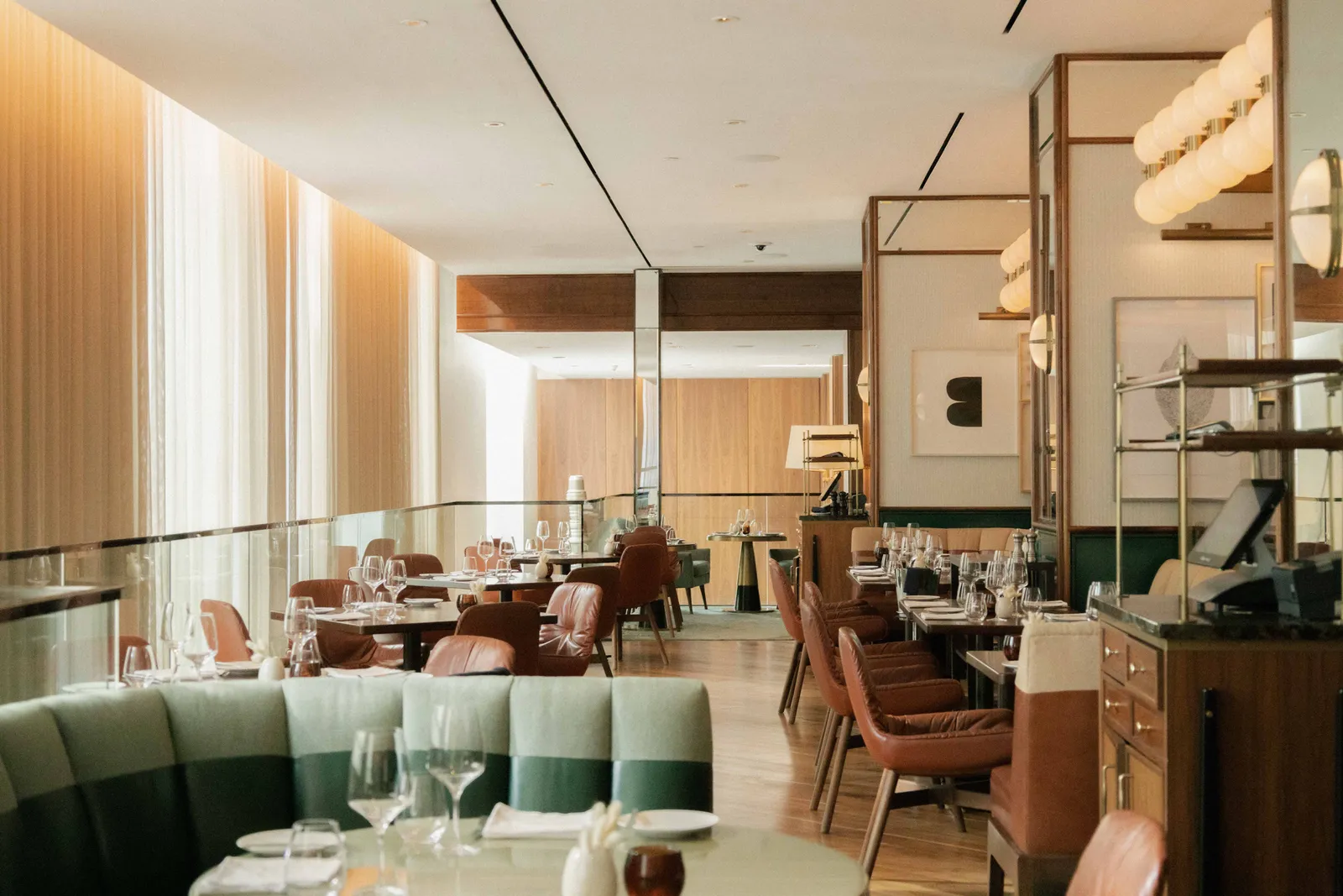 La sala di Café Boulud con divanetti verdi e tavoli apparecchiati