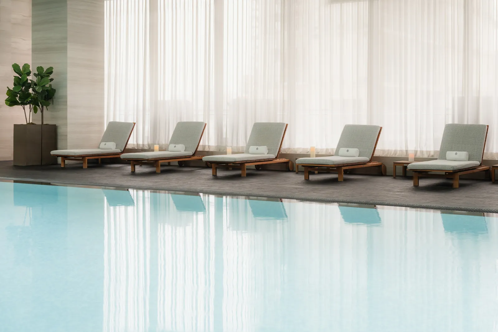 Acqua azzurra e lettini lungo le vetrate della piscina