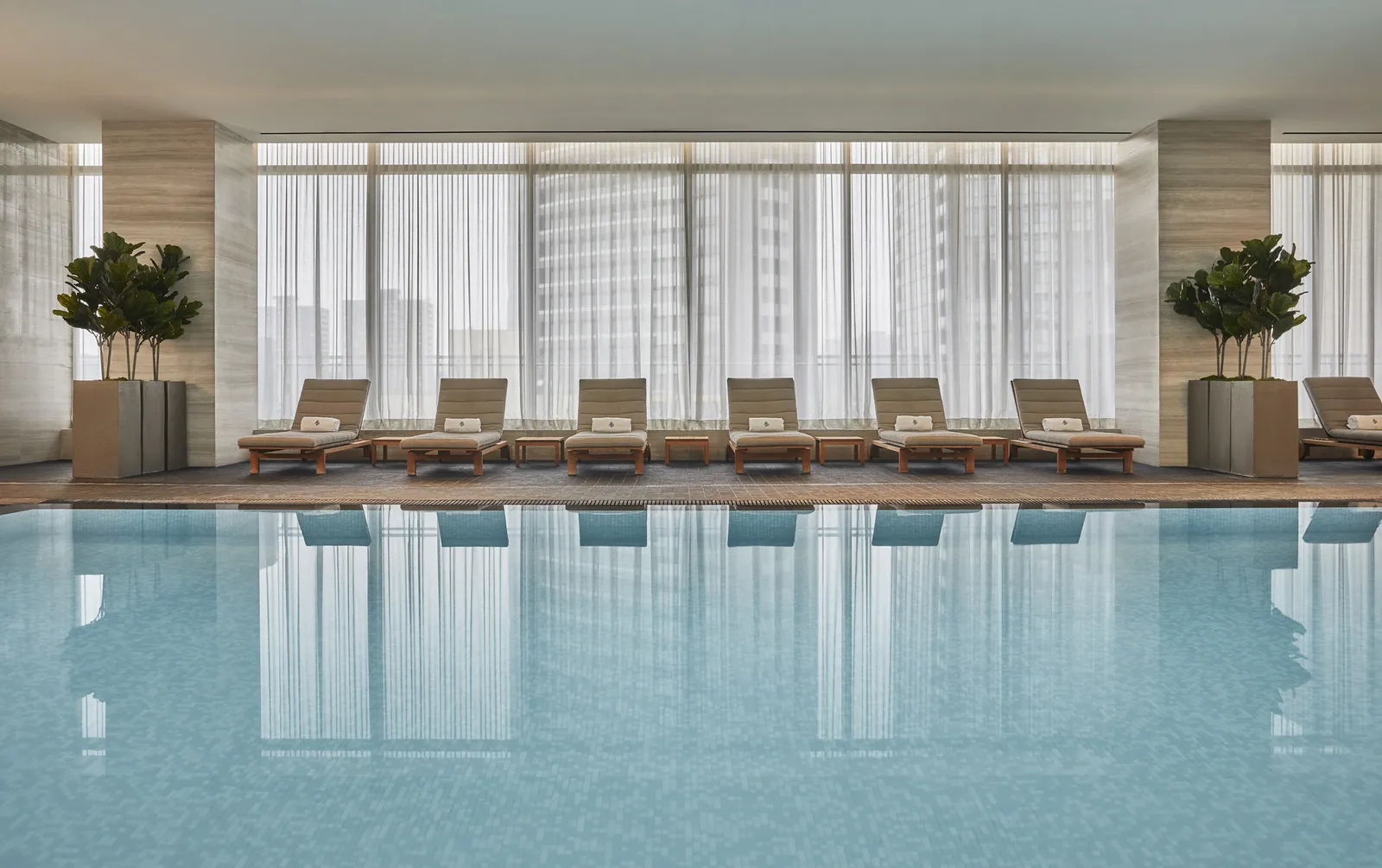 La piscina interna, i lettini chiari e le grandi finestre