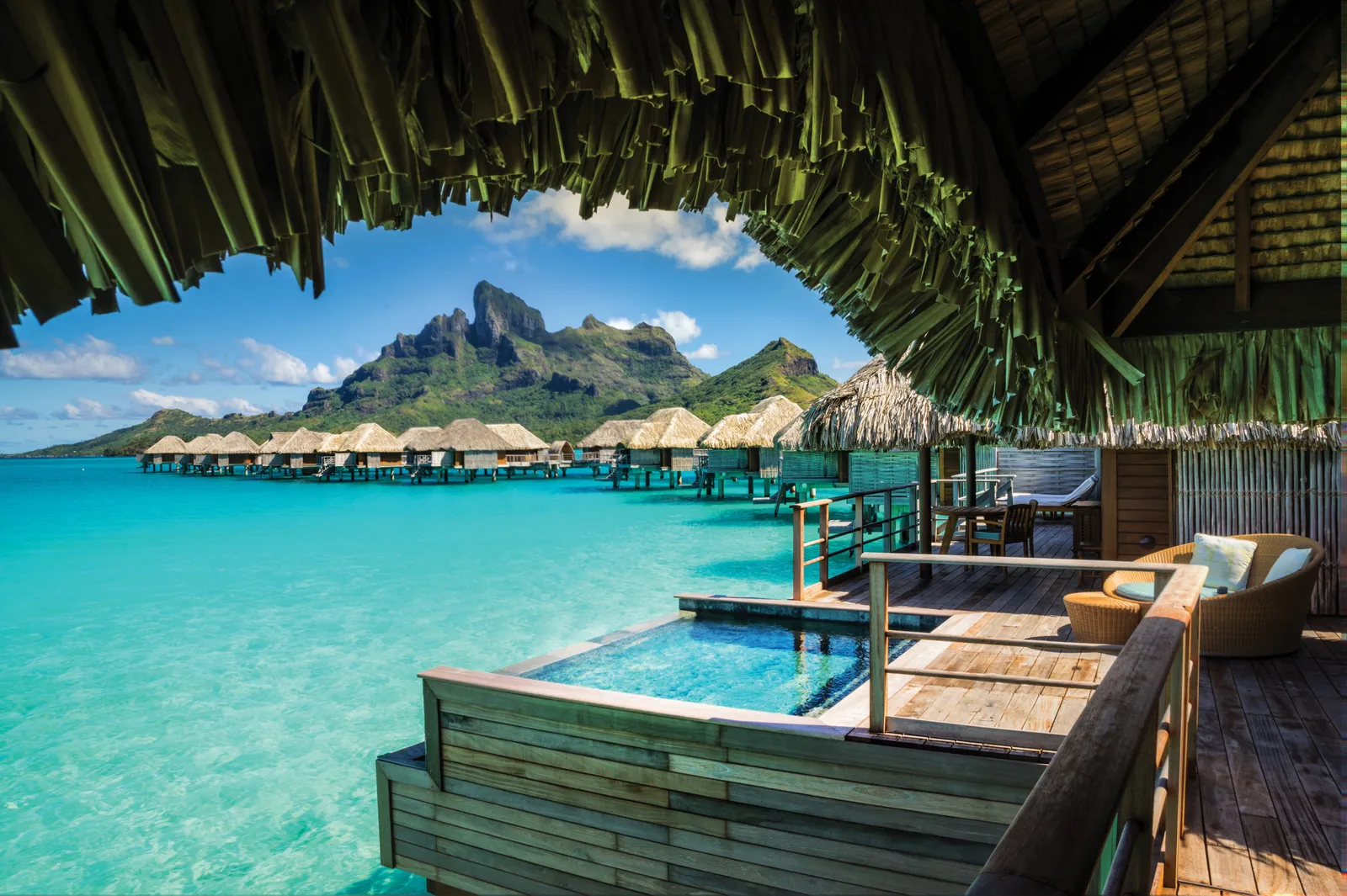 A suite deck with its plunge pool and an armchair, the row of bungalows and Otemanu