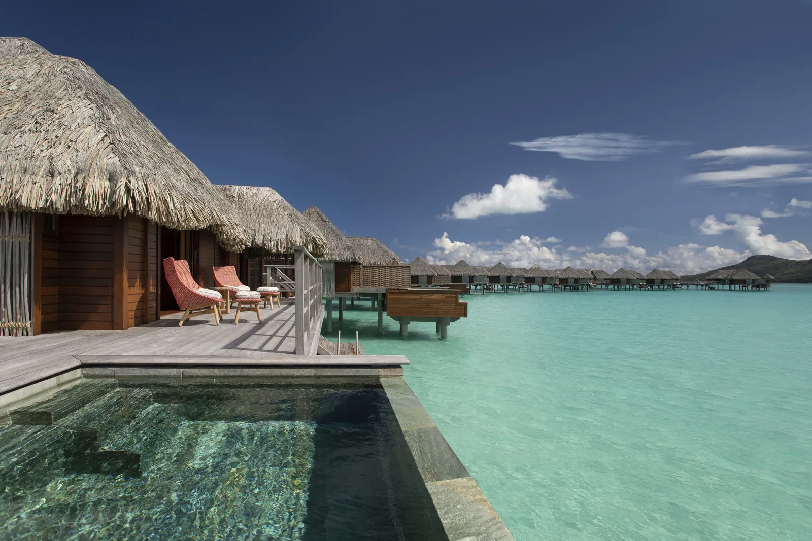 The plunge pool on the deck, between thatched roofs and the turquoise lagoon