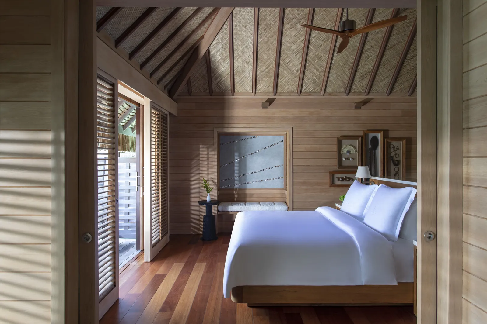A pale-timber bedroom, a white bed and half-open shutters