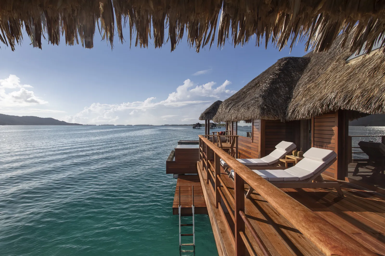 A shaded deck with loungers and a ladder down into the lagoon