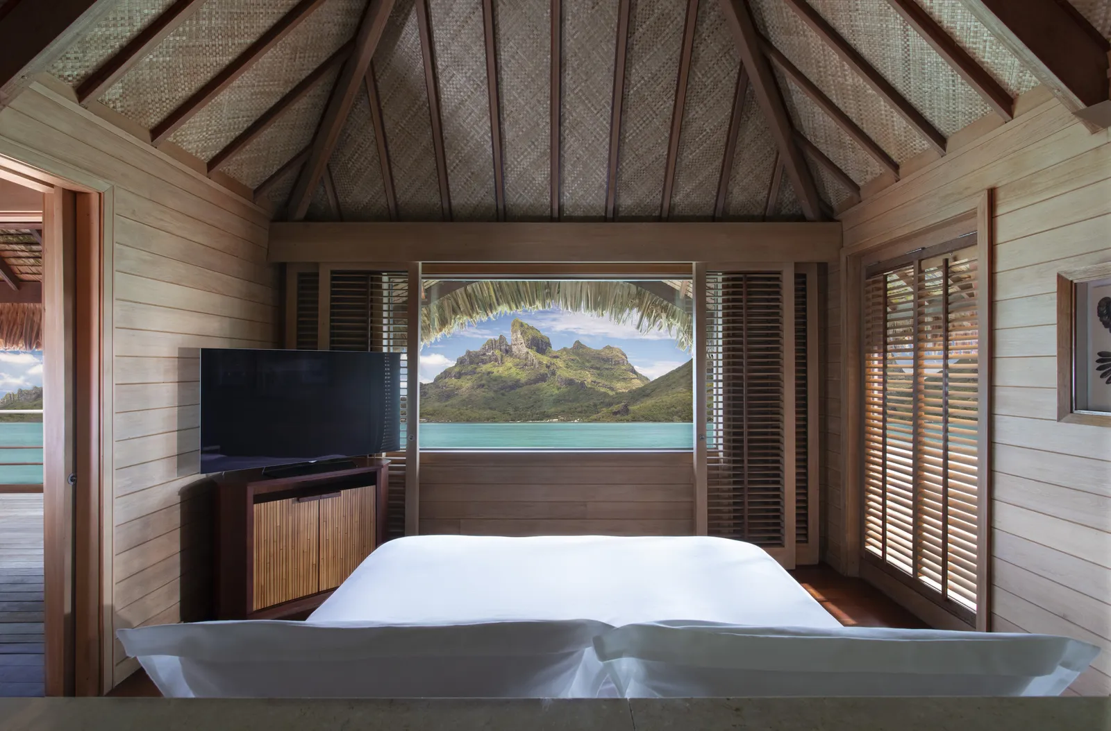 A bed facing a window that frames Mount Otemanu