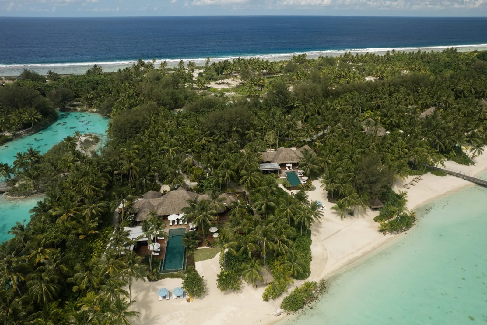 A beachfront villa from above, its pool among the palms
