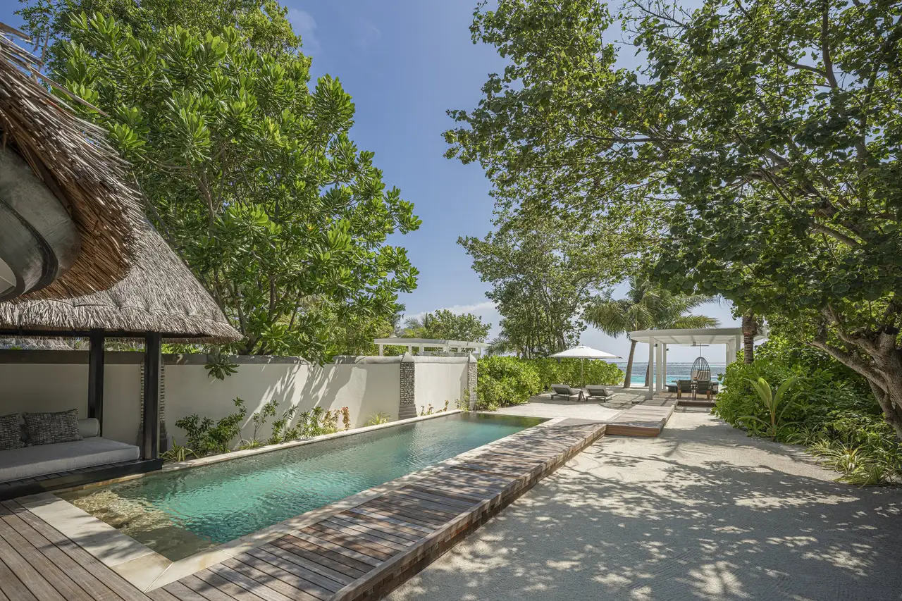 A Sunrise Family Beach Villa’s pool among the trees, the sea beyond the wall