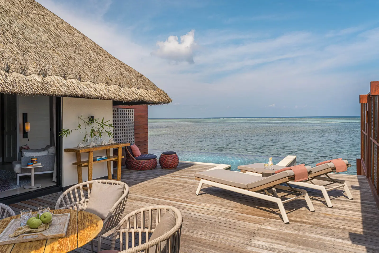The Sunrise Family Water Villa’s deck with its loungers, thatched roof and the sea