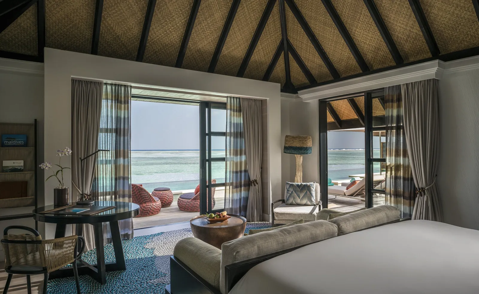 The Sunrise Three-Bedroom Water Suite’s living room, its glass doors onto the sea