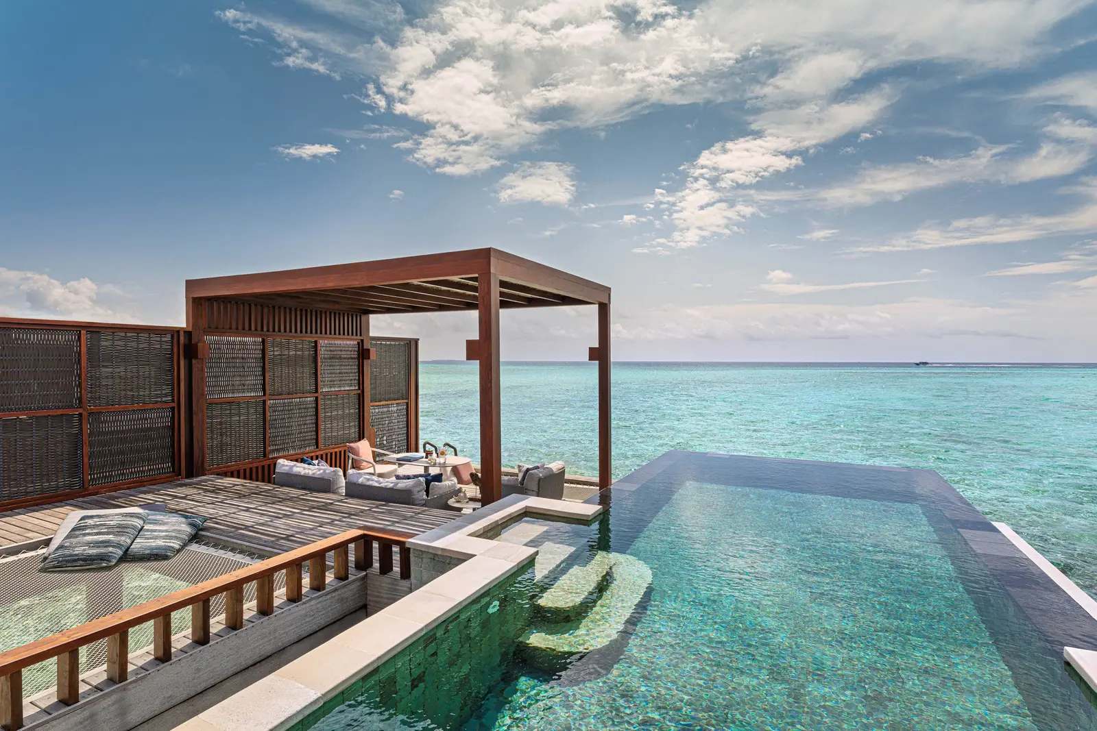 A Sunrise Water Villa’s deck with its infinity pool over the lagoon