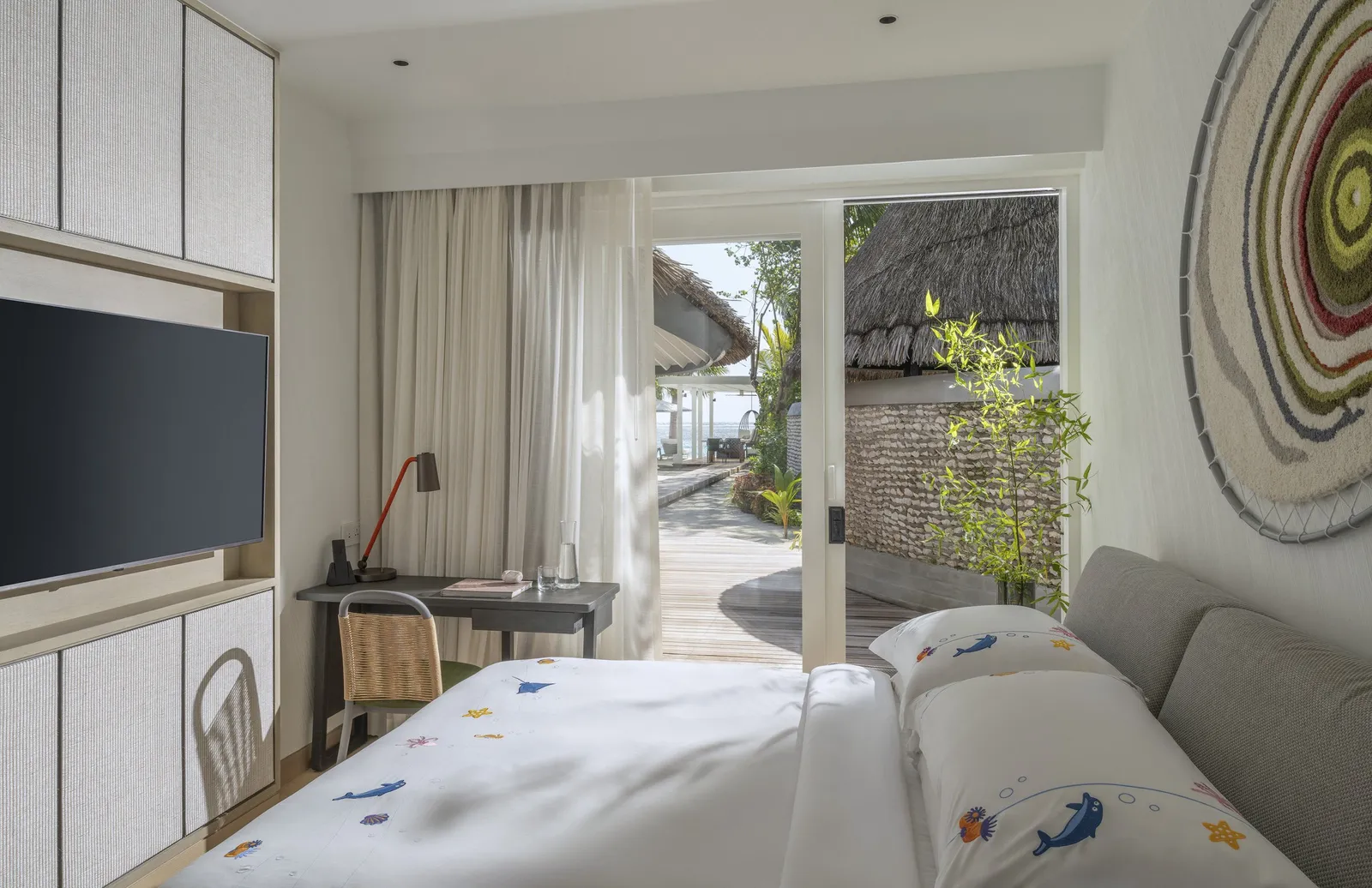 A Sunset Family Beach Villa bedroom, the bed and doors open to the garden