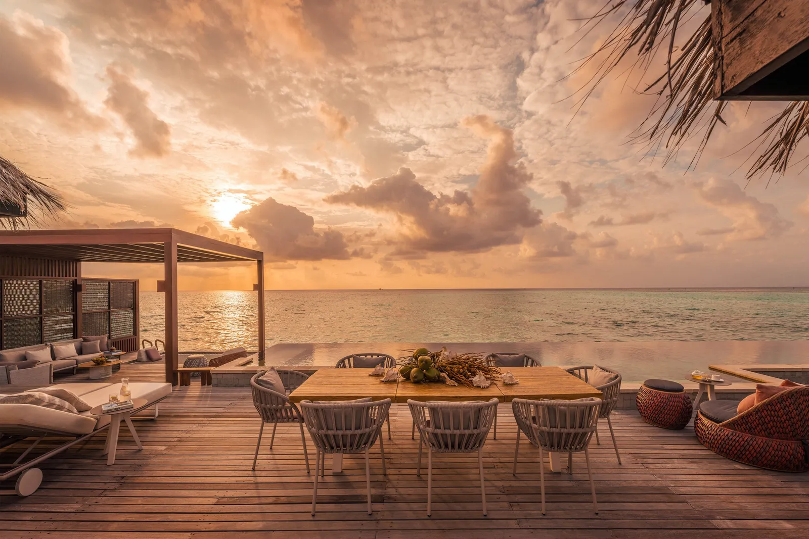 The Sunset Three-Bedroom Water Suite’s deck at sunset, with its dining table