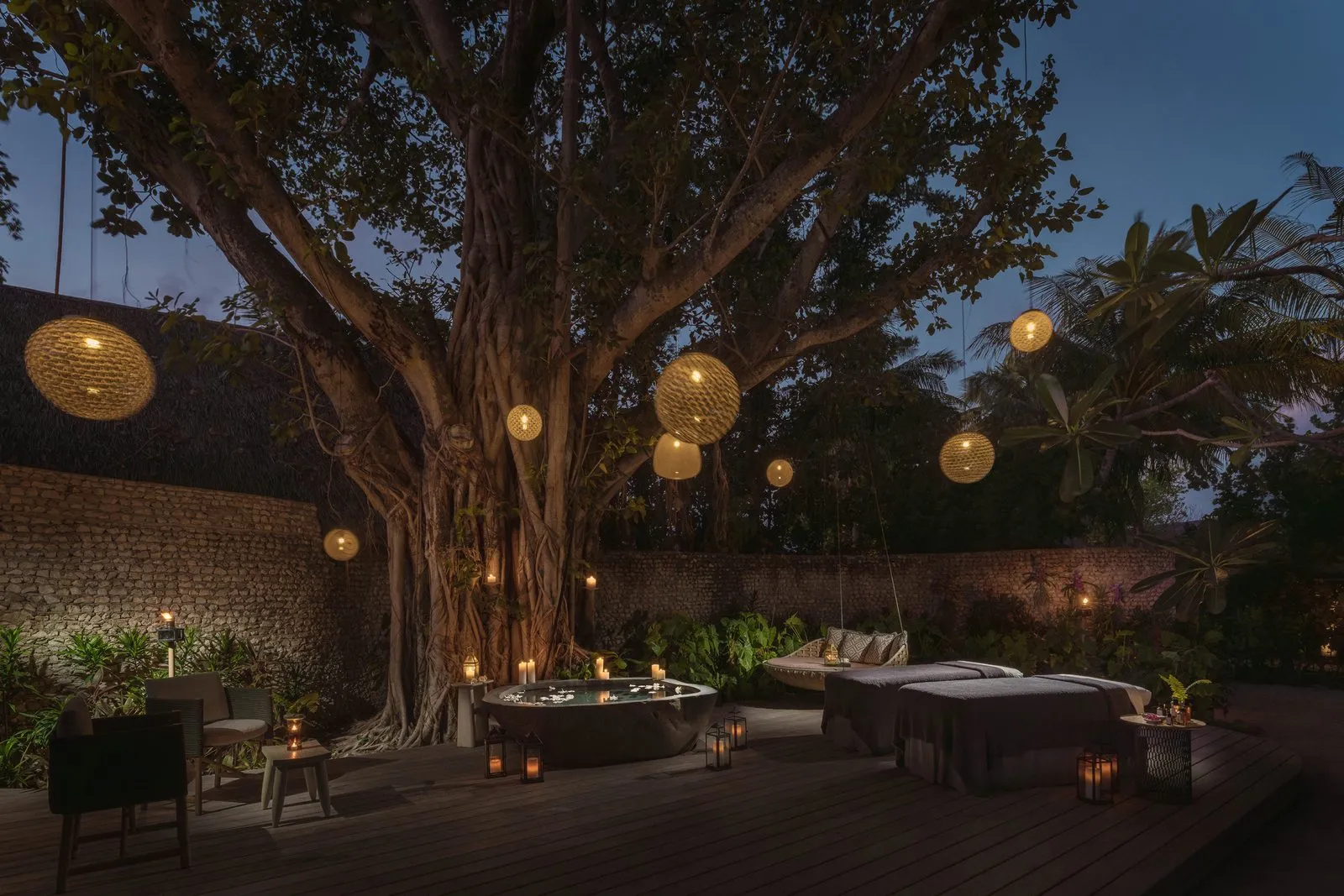 AyurMa’s open-air treatment deck under a great banyan tree: beds, a tub and a hanging daybed