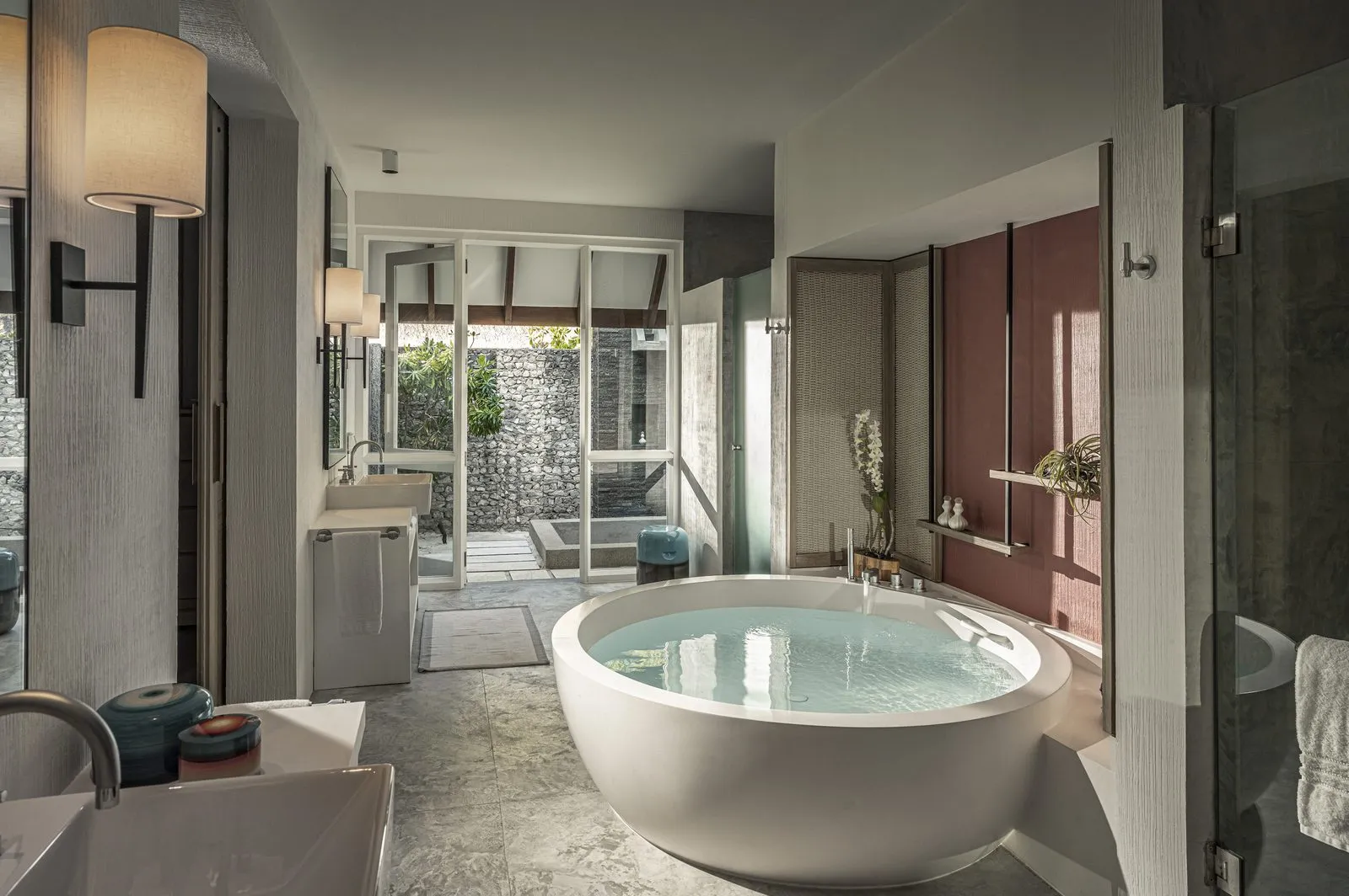 A Beach Villa’s bathroom, its large round tub and the door open to the outdoor shower