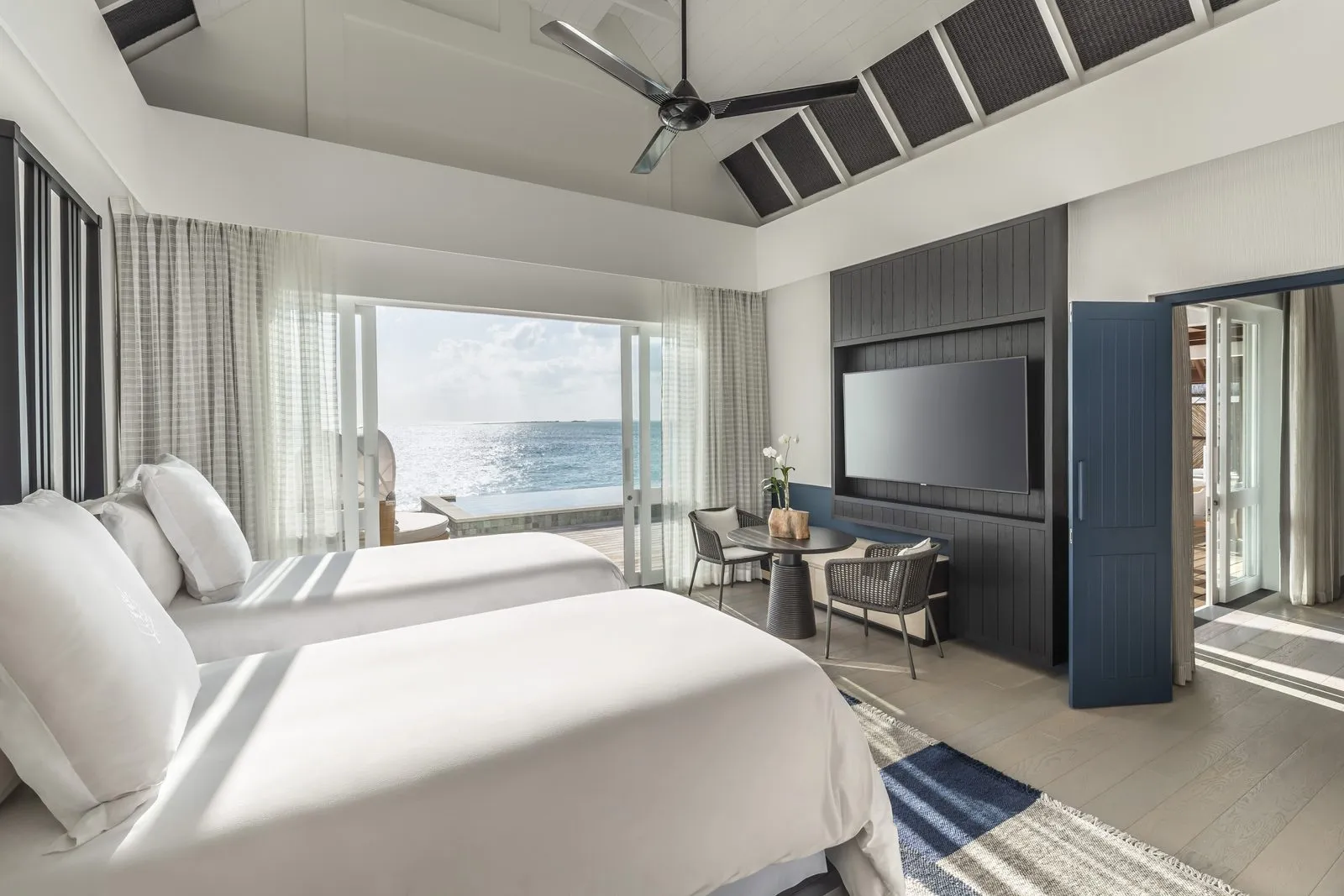 A Sunset Water Villa’s bedroom, twin beds and the view over the ocean