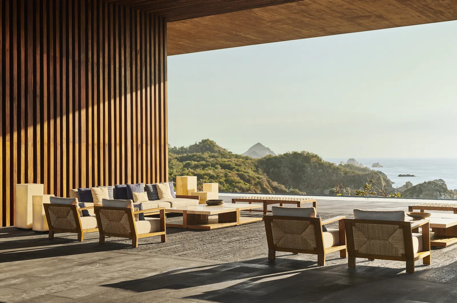 La terrazza di La Mansión, con poltrone fra pareti di legno e vista sul mare
