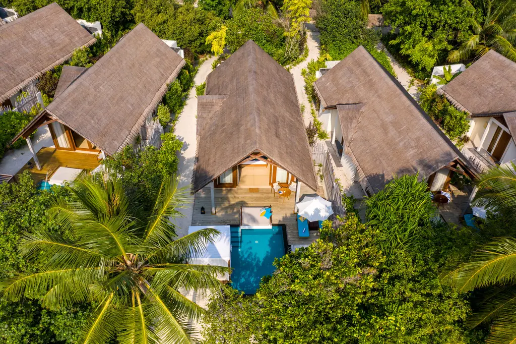 The Beach Pool Villas from above: thatched roofs and pools among the palms