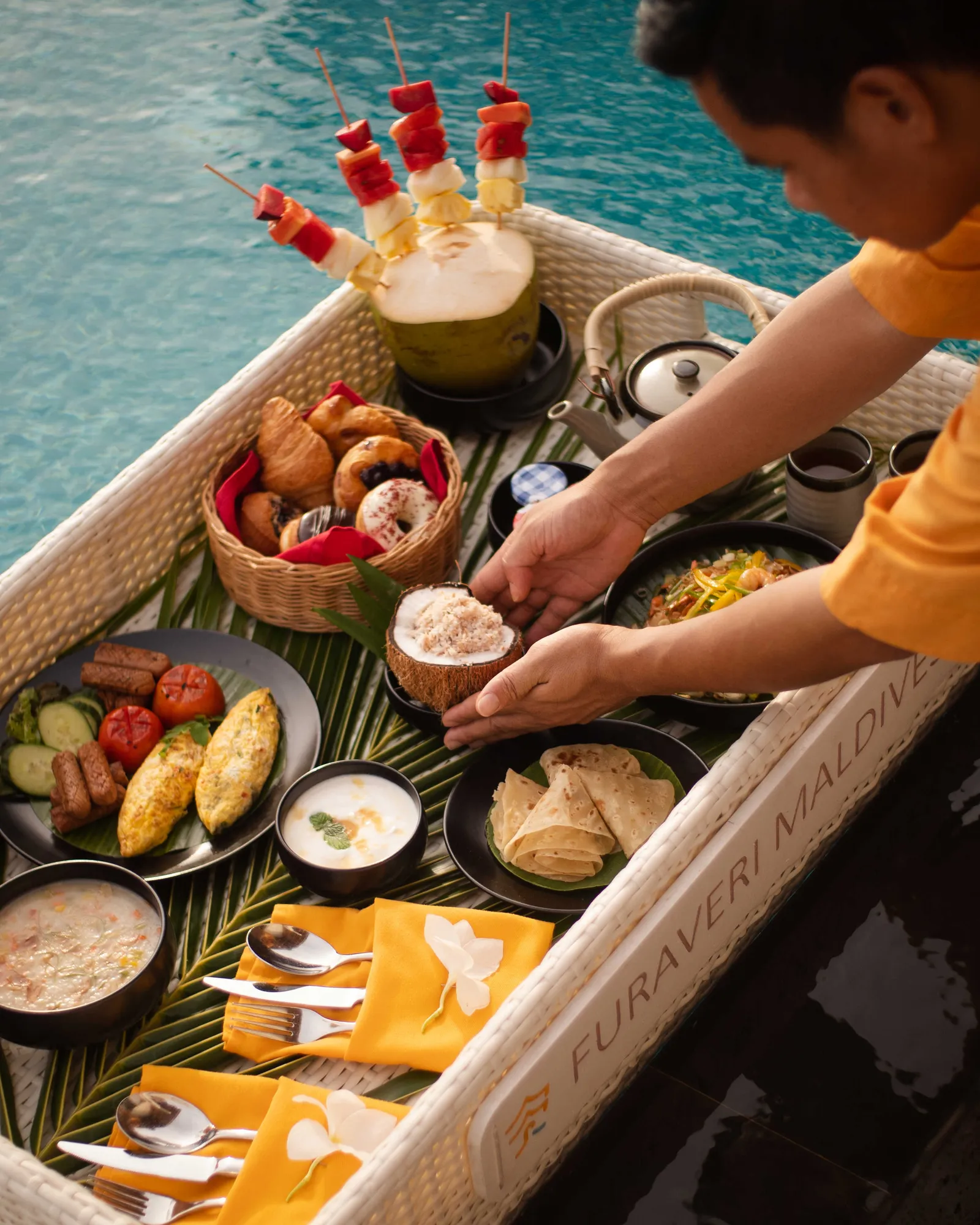 The floating breakfast served in a pool: fruit, eggs, pastries and coffee on a tray