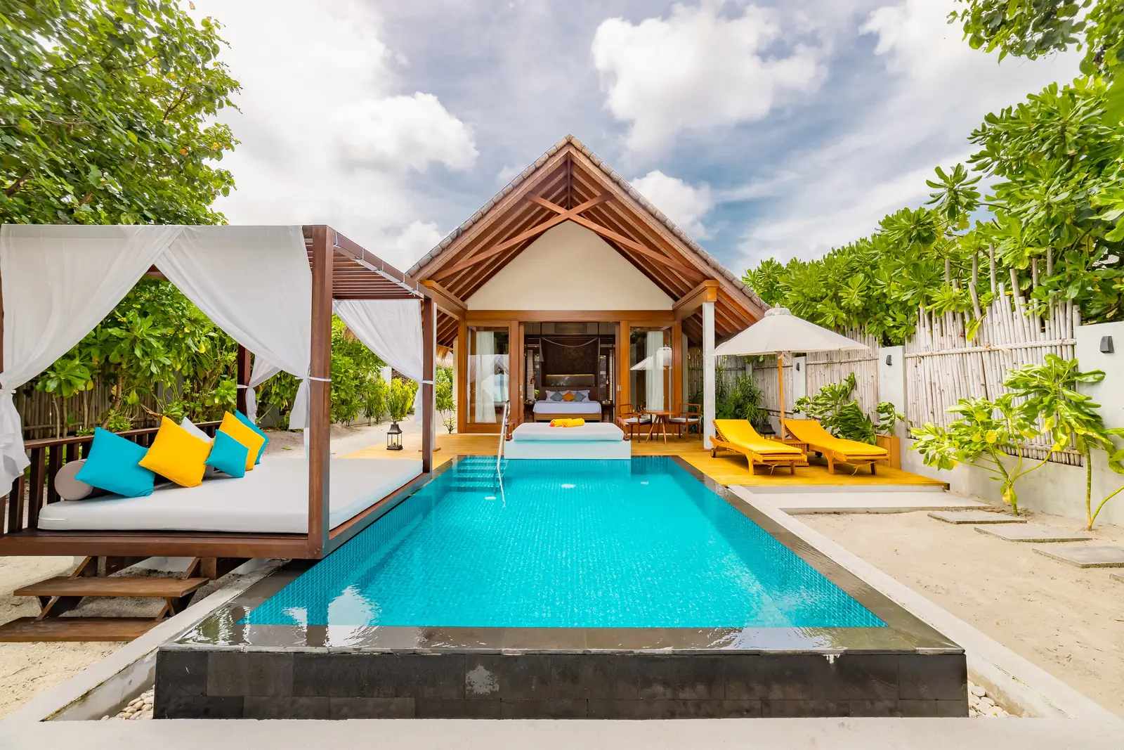 A Beach Pool Villa’s pool in front of its timber pavilion, the white daybed on the left