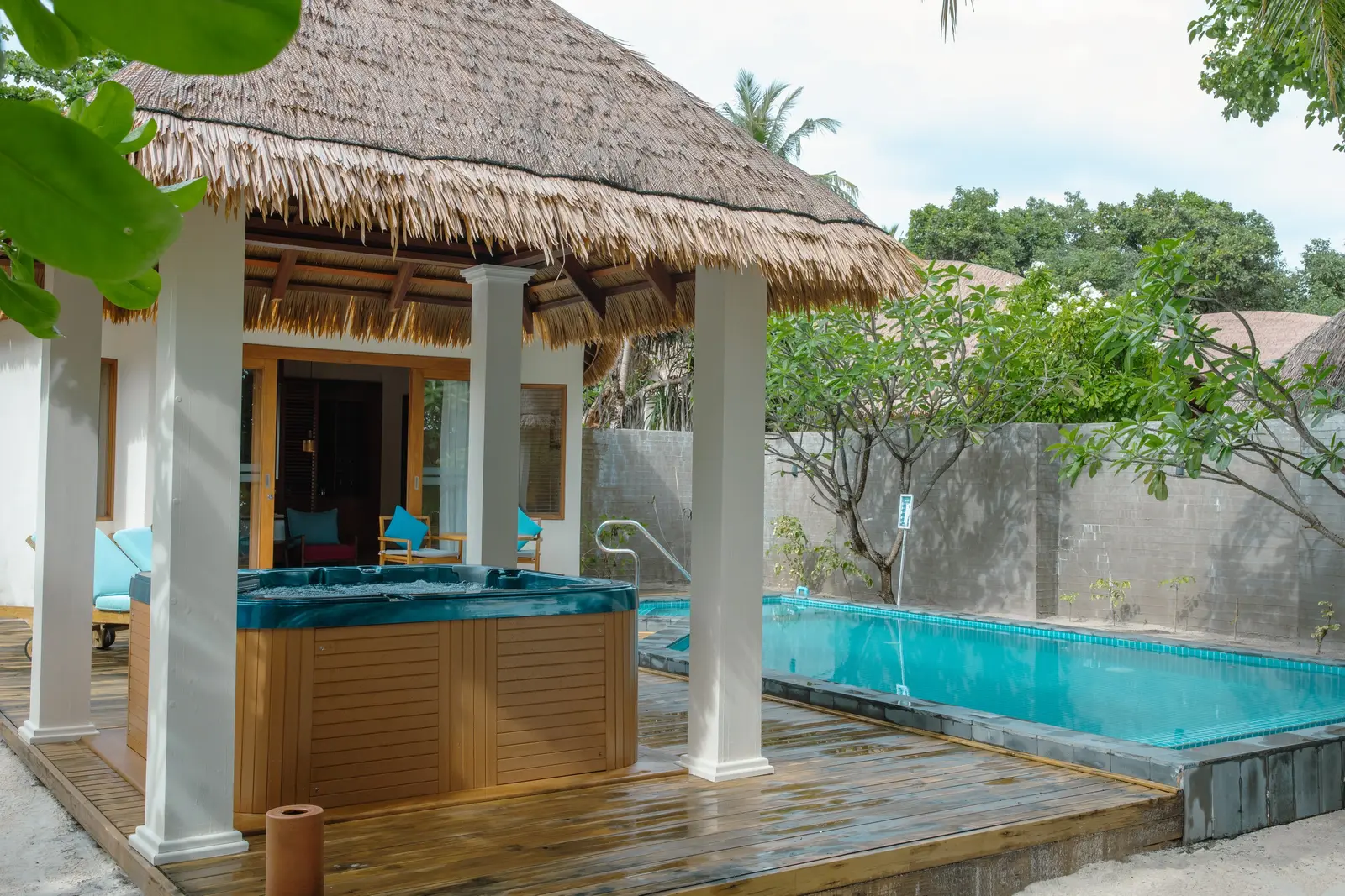 The jacuzzi under its thatch and the long pool of a Beach Pool Villa with Jacuzzi