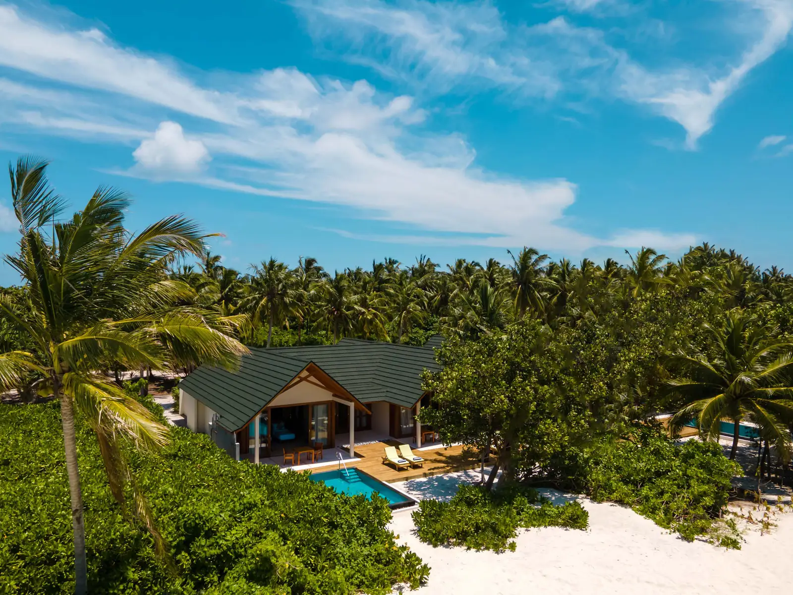 A 2-bedroom residence from the air, its pool among the palms a step from the beach