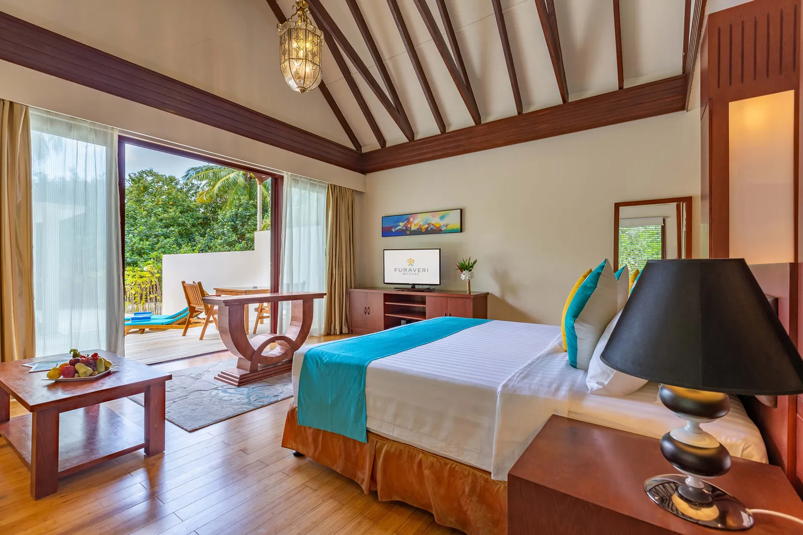 A Garden Villa bedroom, the bed with its turquoise throw and the glass door onto the greenery