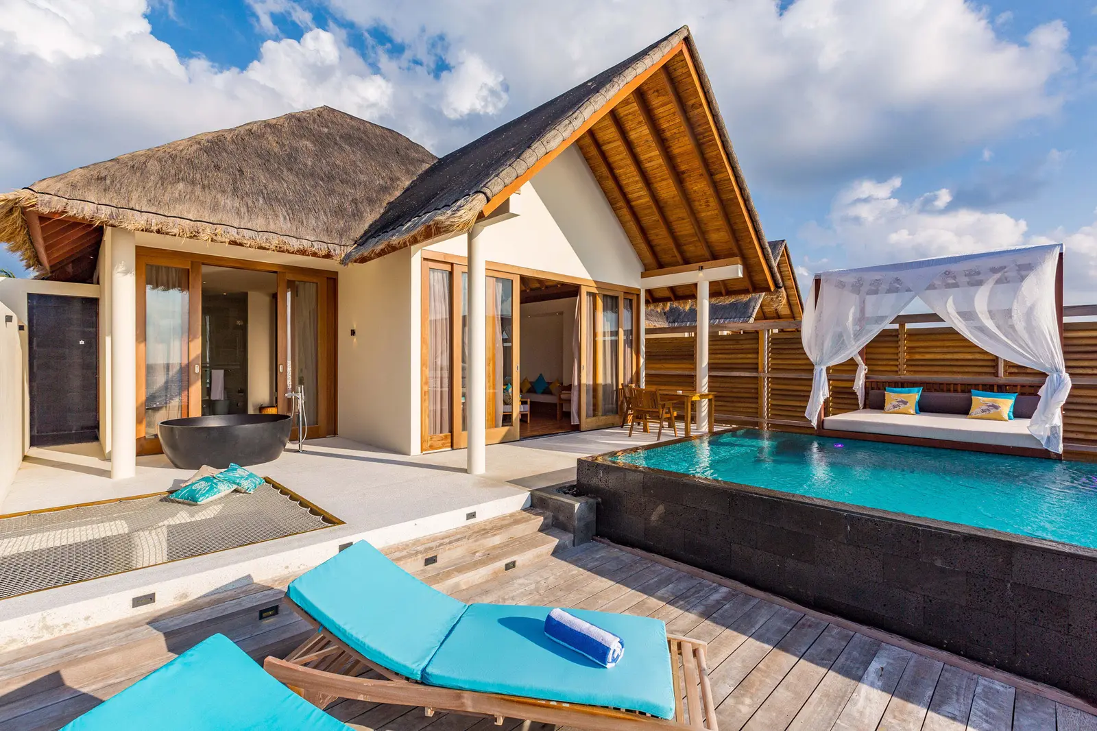 The pool, canopy bed and open-air bathtub of a Sunrise Ocean Pool Villa