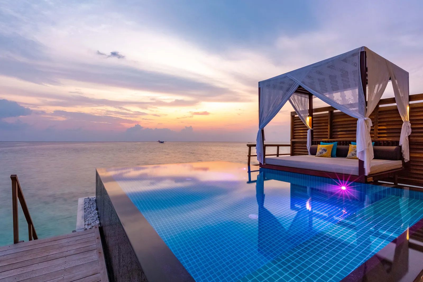The infinity pool of a Sunset Ocean Pool Villa at sunset, the canopy daybed on the deck