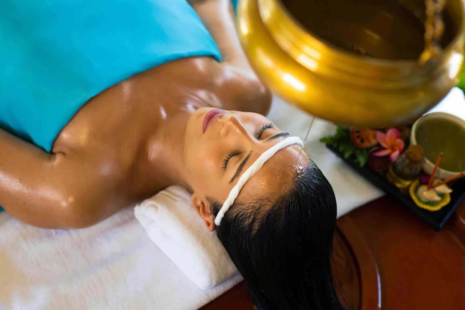 A shirodhara: warm oil poured on the forehead from a brass vessel