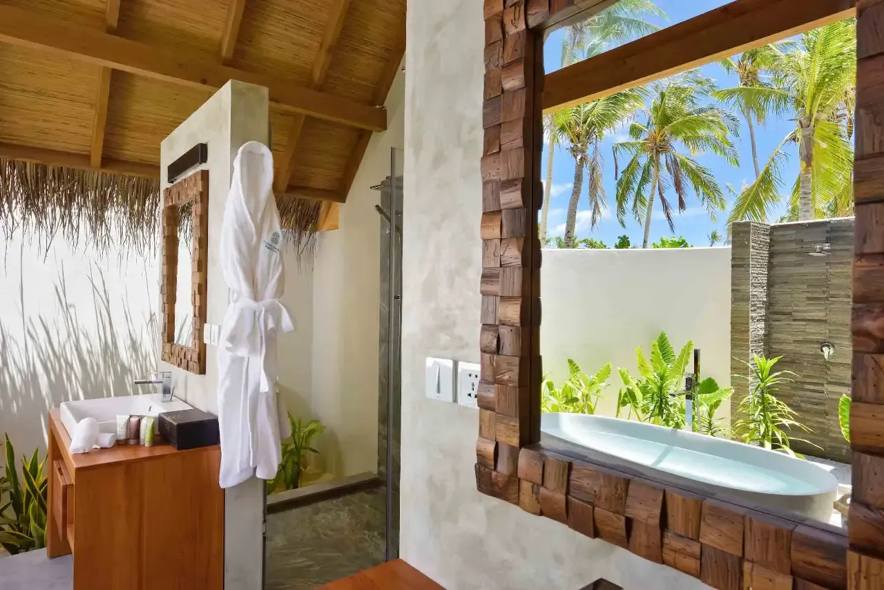 The open-air bathroom of a Beach Villa Sunrise, the bath beneath a window onto the garden.