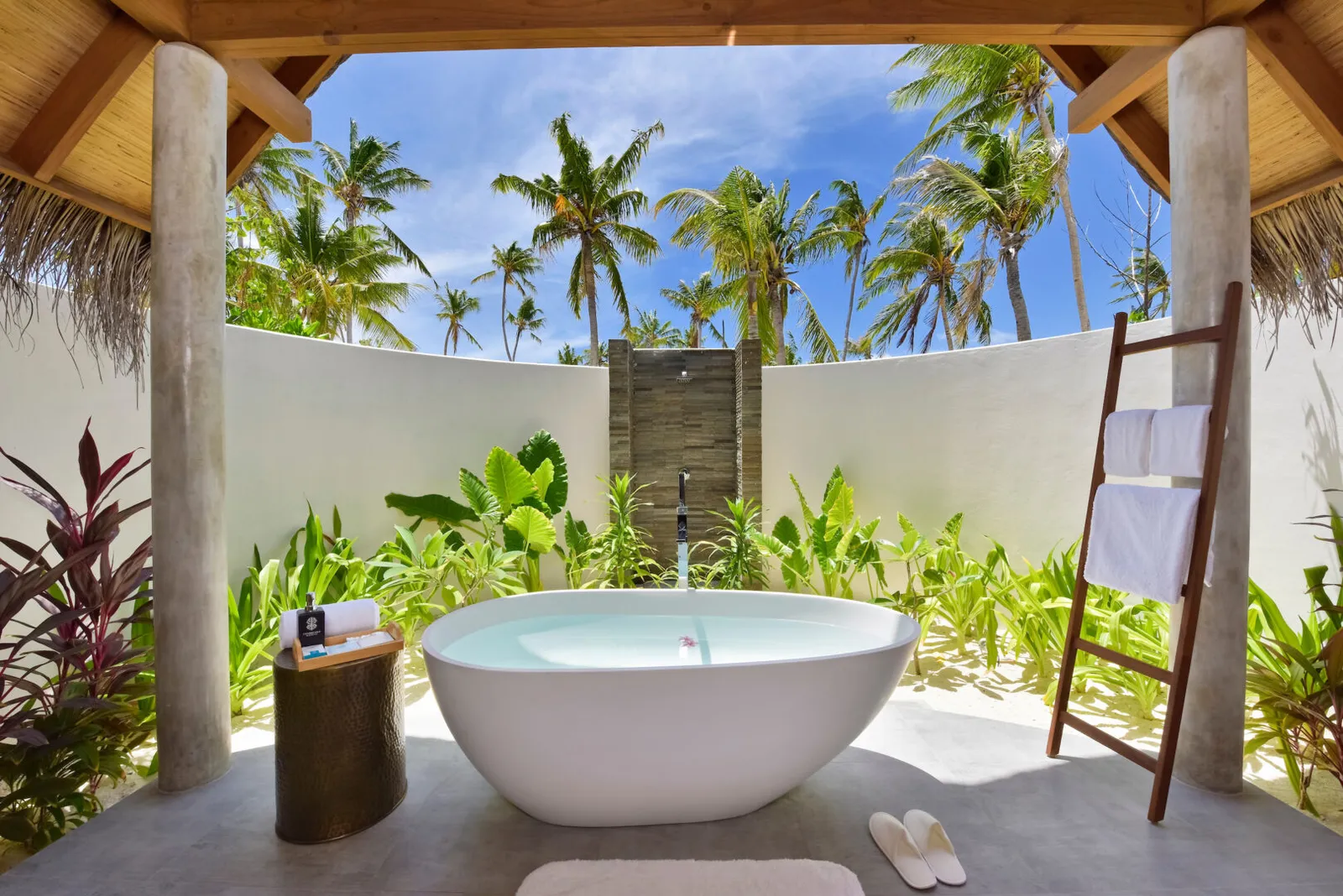 The open-air bathroom of a Pool Beach Villa Sunset, the bath among the plants.