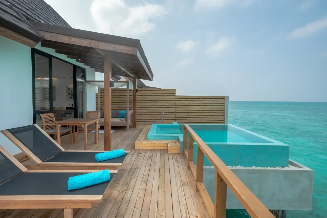 The deck of a Pool Water Villa, with loungers and an infinity pool over the sea.