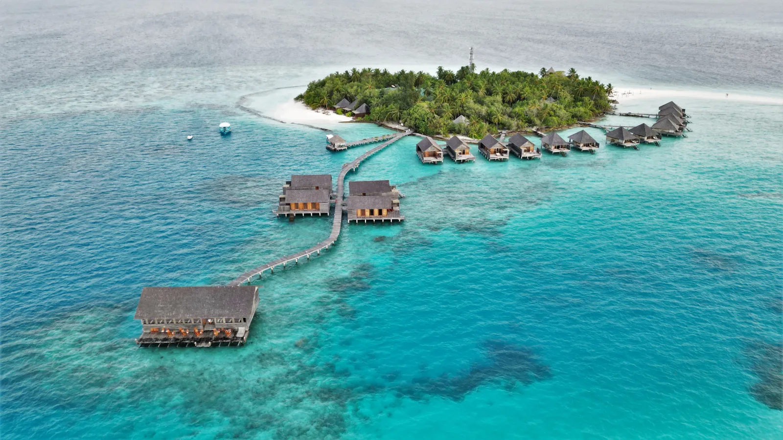 Gangehi from above: the small green island with its white beach, the row of overwater villas and the jetty out to a pavilion in the lagoon.