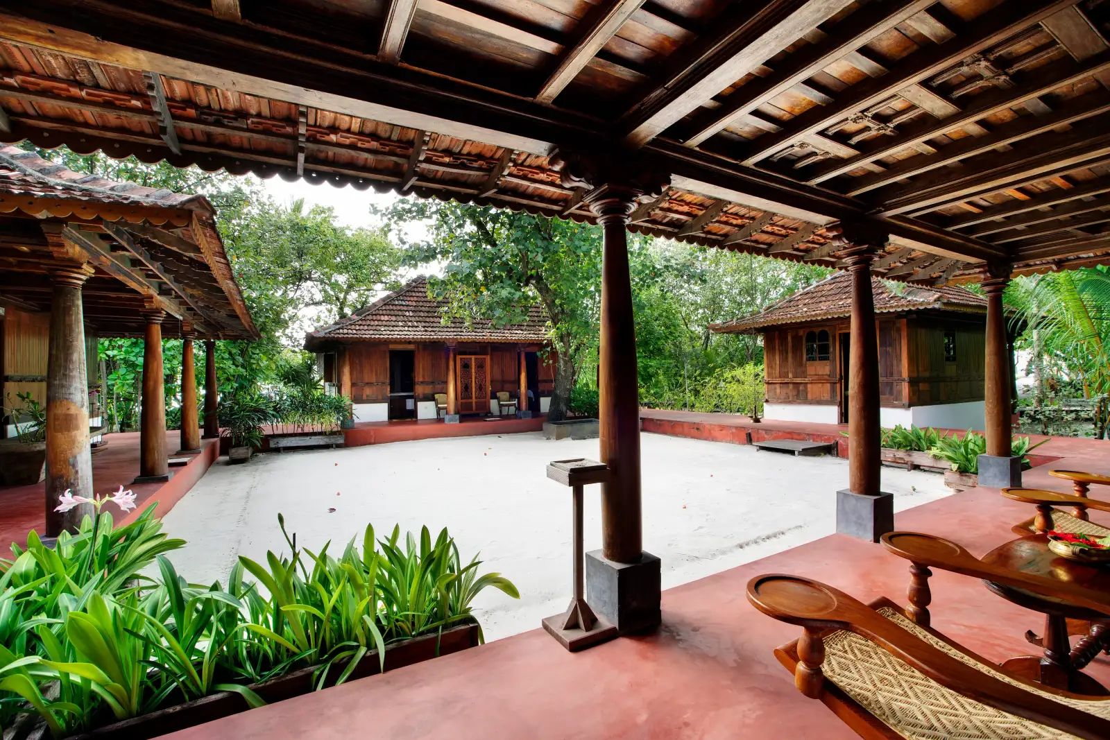 The Ginger Spa’s courtyard seen from its timber portico: the tiled pavilions among the trees and the white sand.