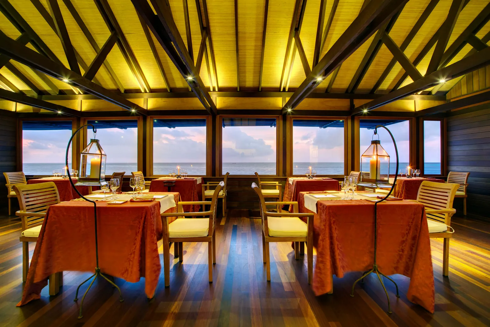 Thari’s dining room laid with orange tablecloths under the timber roof, its windows on the sea.