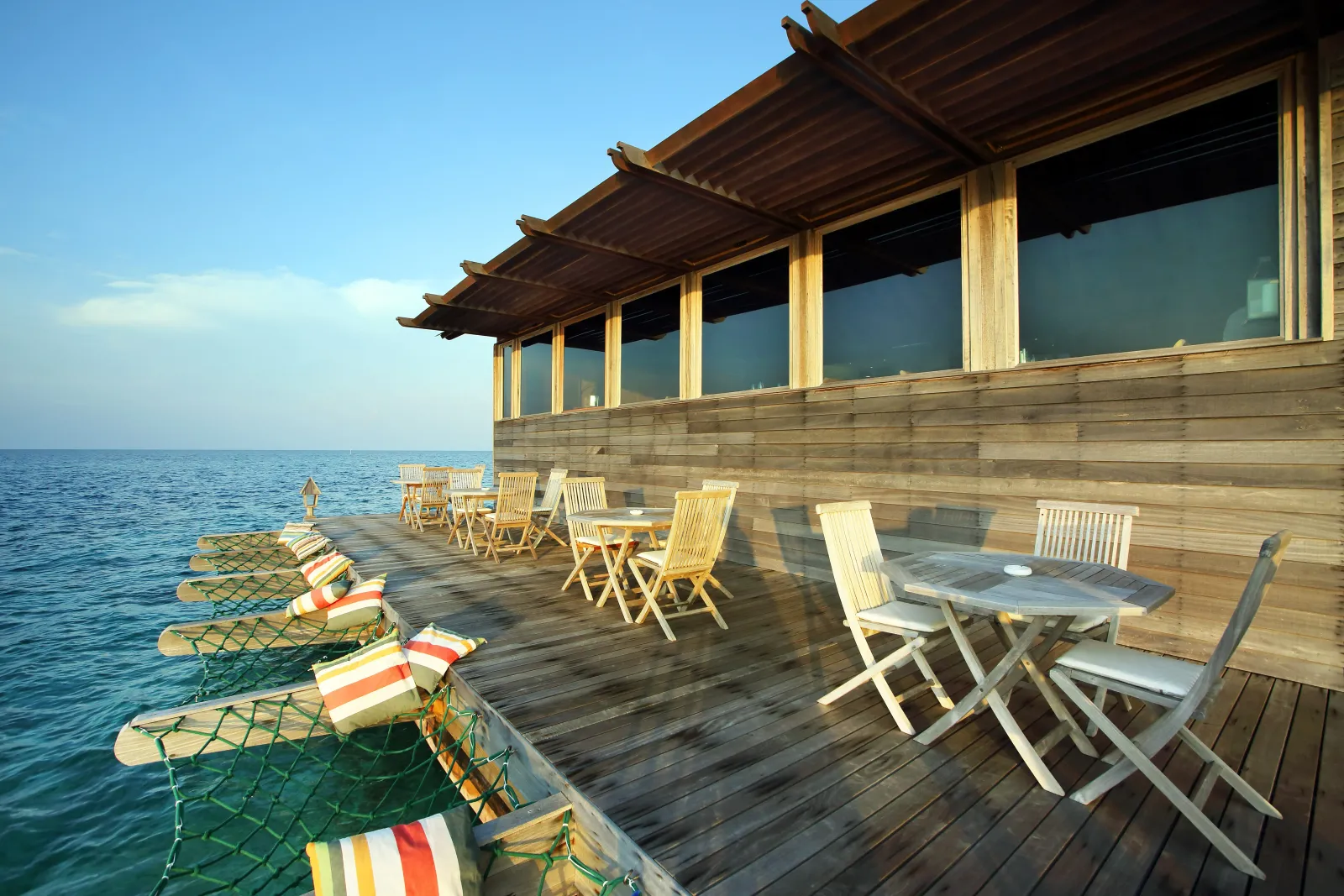 The wooden terrace over the sea, with its small tables, folding chairs and nets slung above the water.