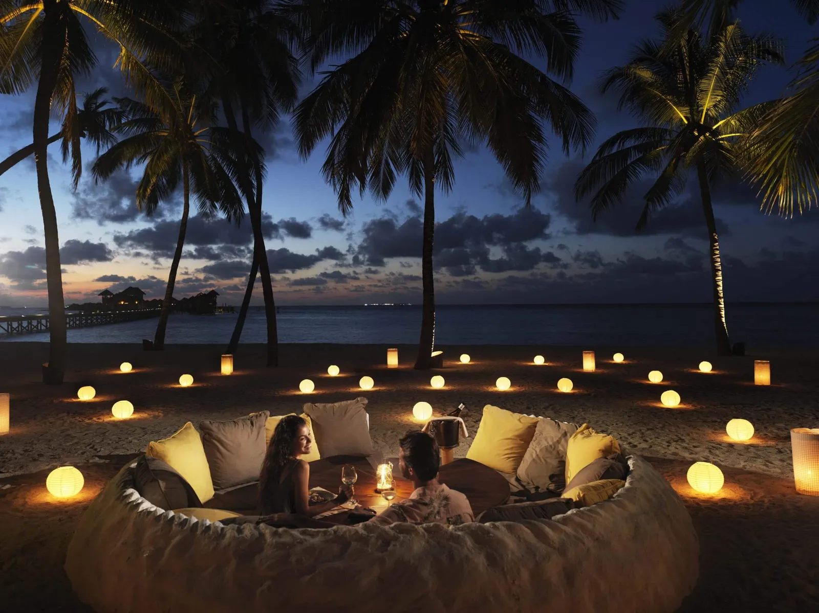 A couple dining under the stars, in a ring of candles on the sand