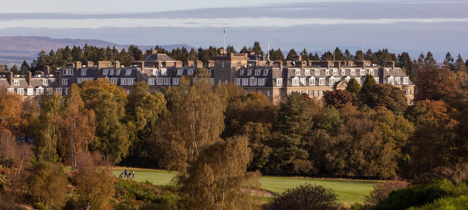 The hotel among the estate’s autumn trees, with the hills behind