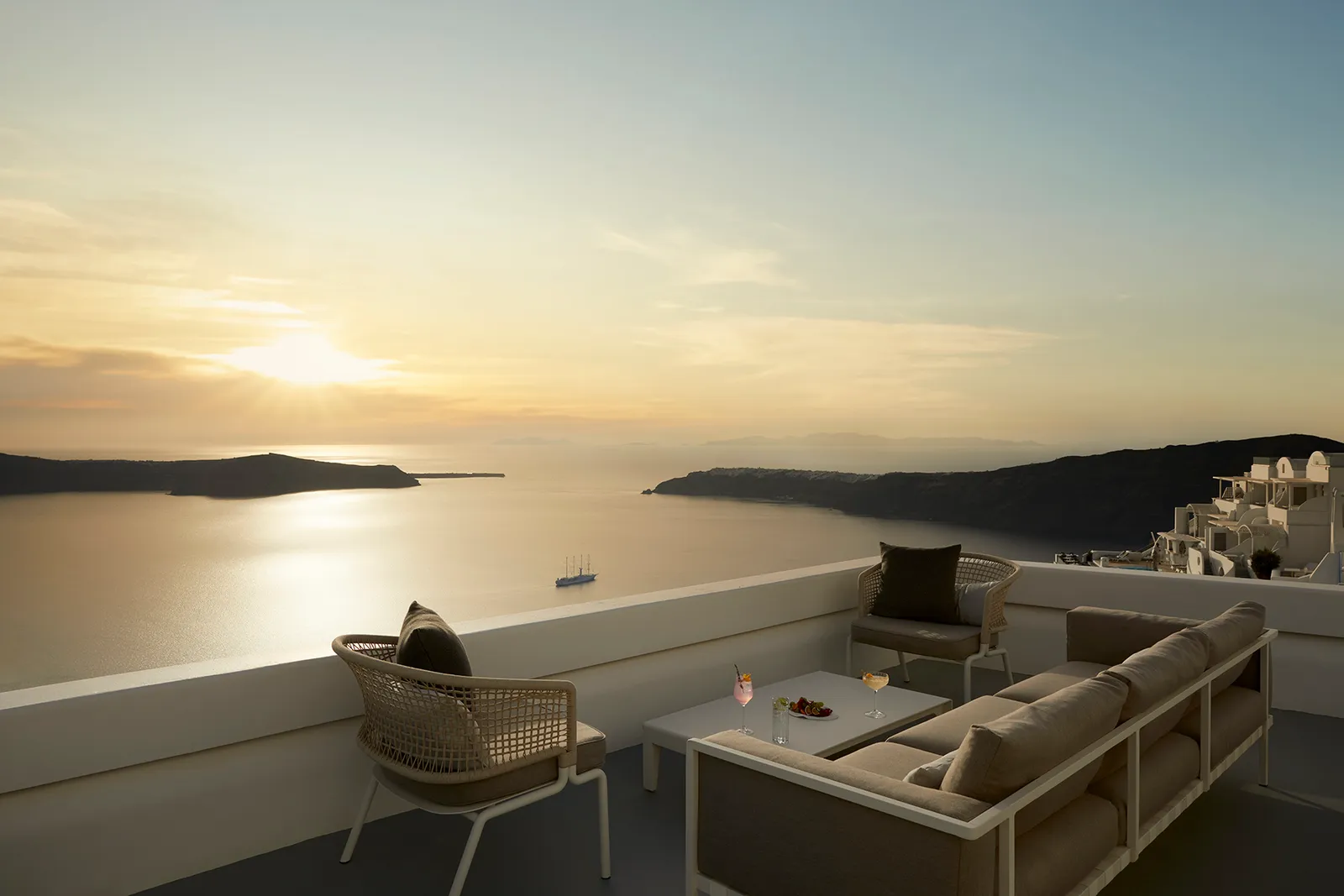 The 363 Bar terrace at sunset, its sofas and rope armchairs facing the low sun over the caldera.