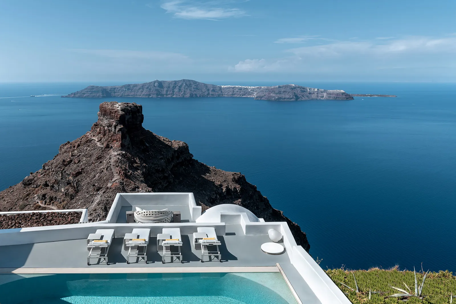The Villa’s pool and loungers from above, with Skaros Rock, the blue sea and the island of Thirassia on the horizon.