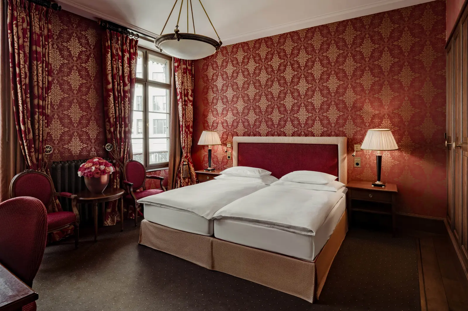 The twin beds of the City King Room between red walls
