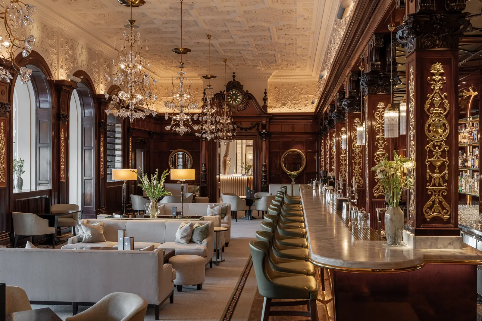 The Cadier Bar: the long marble counter with green stools, columns of dark wood and gilt, crystal chandeliers and pale sofas.