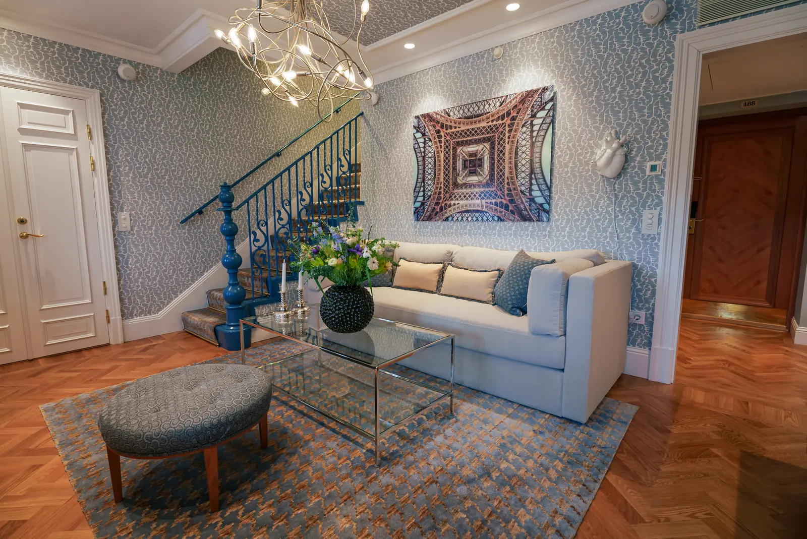 An Attic Suite sitting room: a pale sofa under a large photograph, blue patterned walls and the blue staircase up to the bedroom.