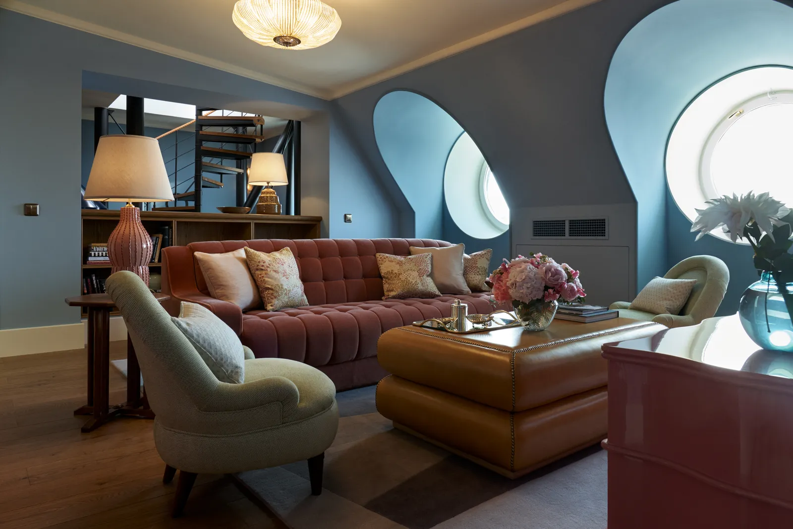 The Flag Suite sitting room: a burgundy velvet sofa, blue walls, 2 oval windows and the spiral staircase up to the lookout.