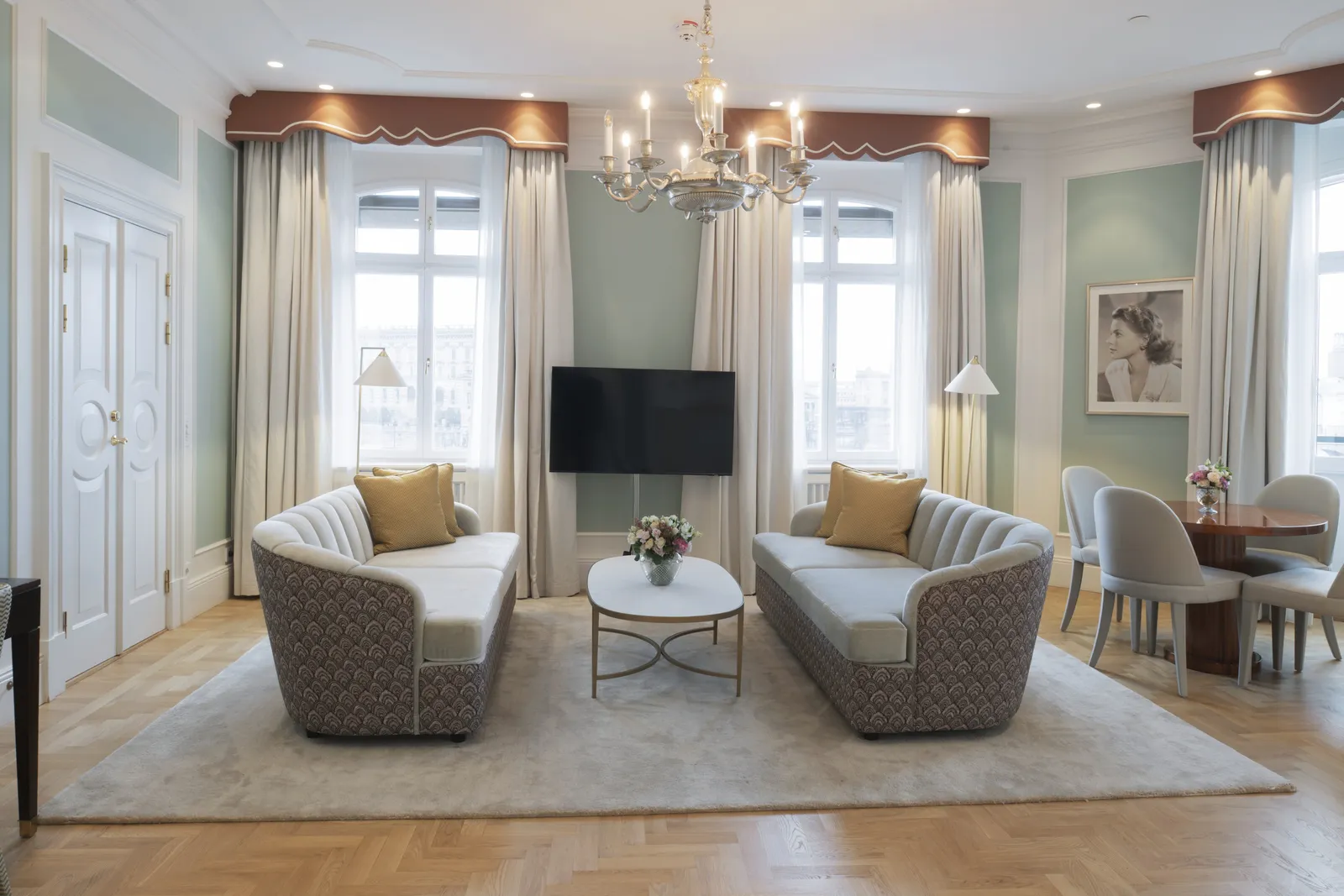 The Ingrid Bergman Suite sitting room: 2 shell-backed sofas around an oval table, pale-green walls and the actress’s portrait by the window.