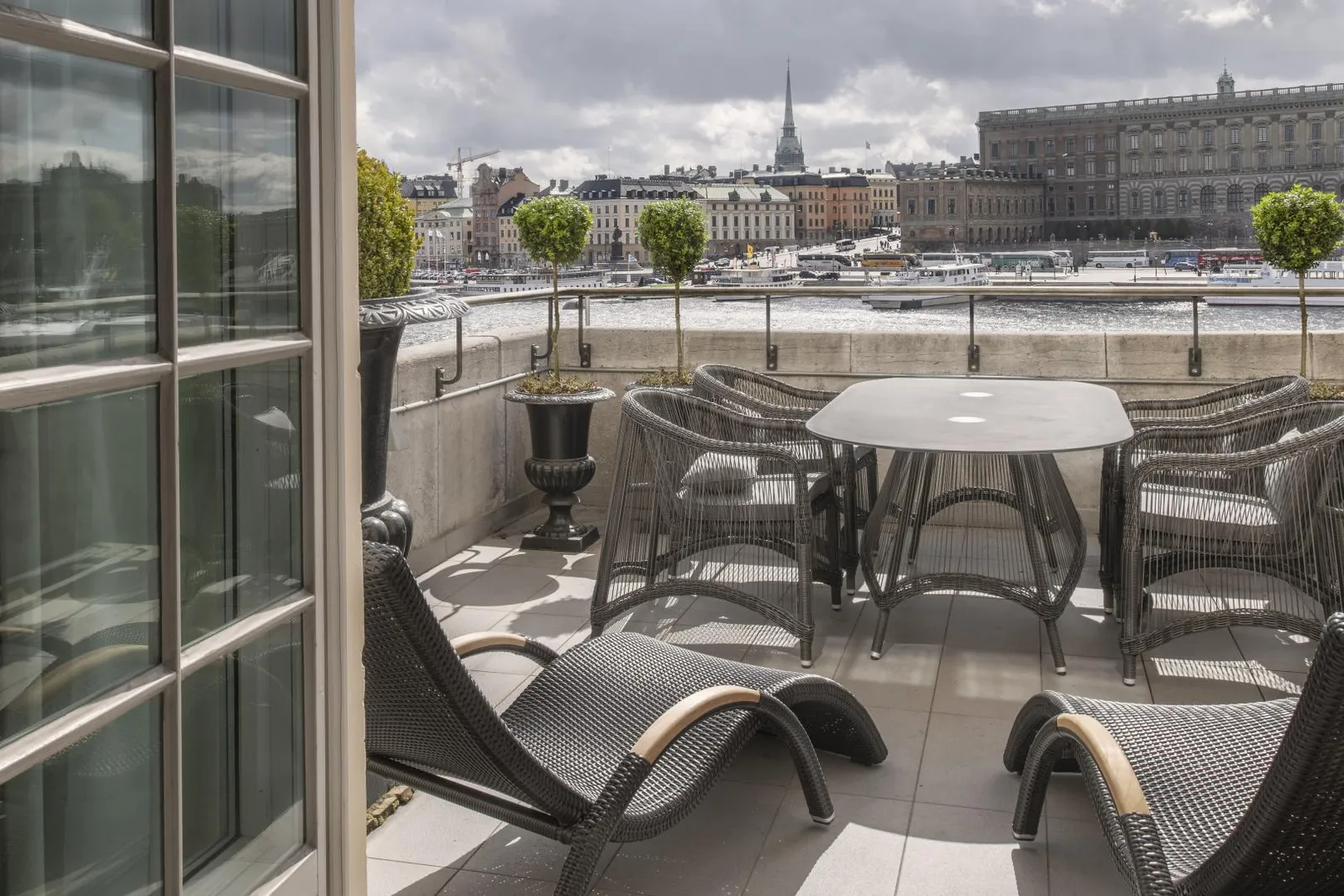 The Terrace Suite’s terrace: a table with wicker armchairs, 2 loungers and, beyond the stone parapet, Gamla Stan and the Royal Palace.