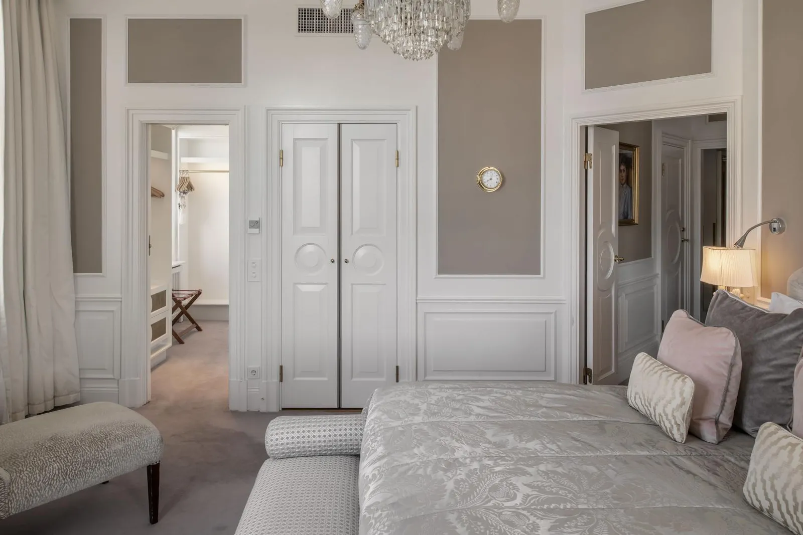 The Wilhelmina Skogh Suite bedroom: the bed with a grey damask cover, white panelled doors and a bench at its foot.
