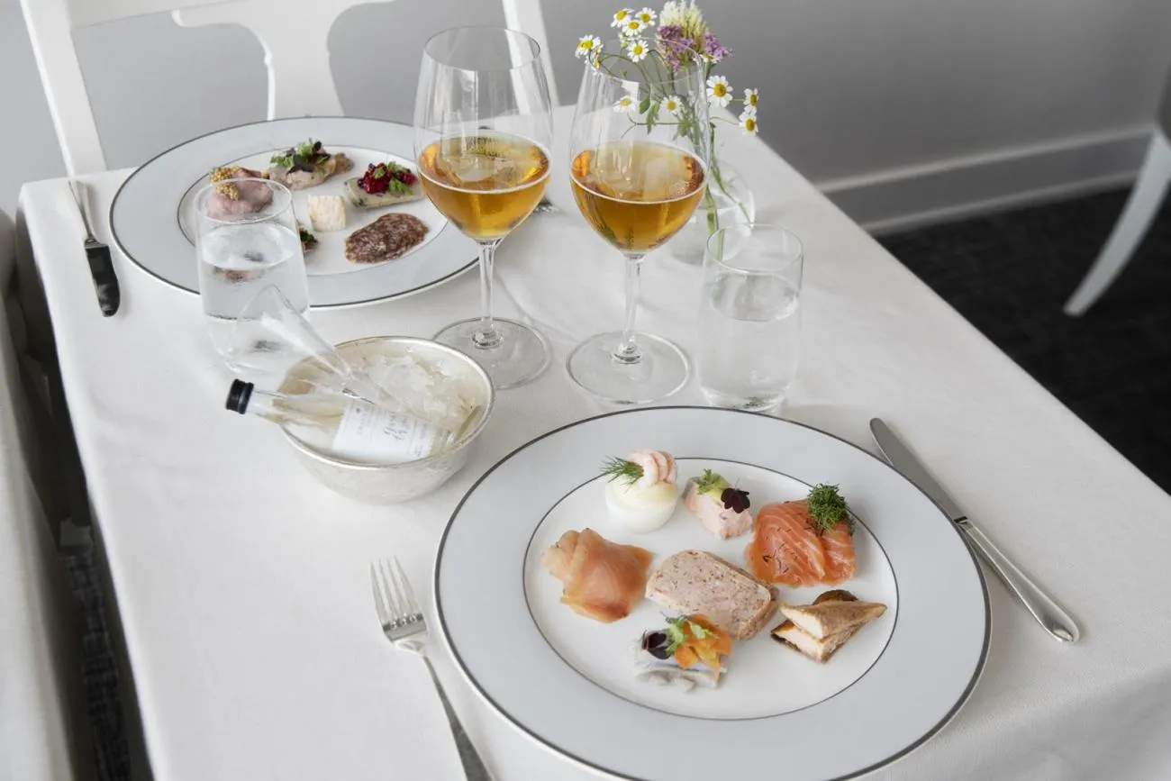 2 plates from the Veranda’s smörgåsbord, with salmon, herring and pâté, beside 2 glasses of beer and an aquavit on ice.
