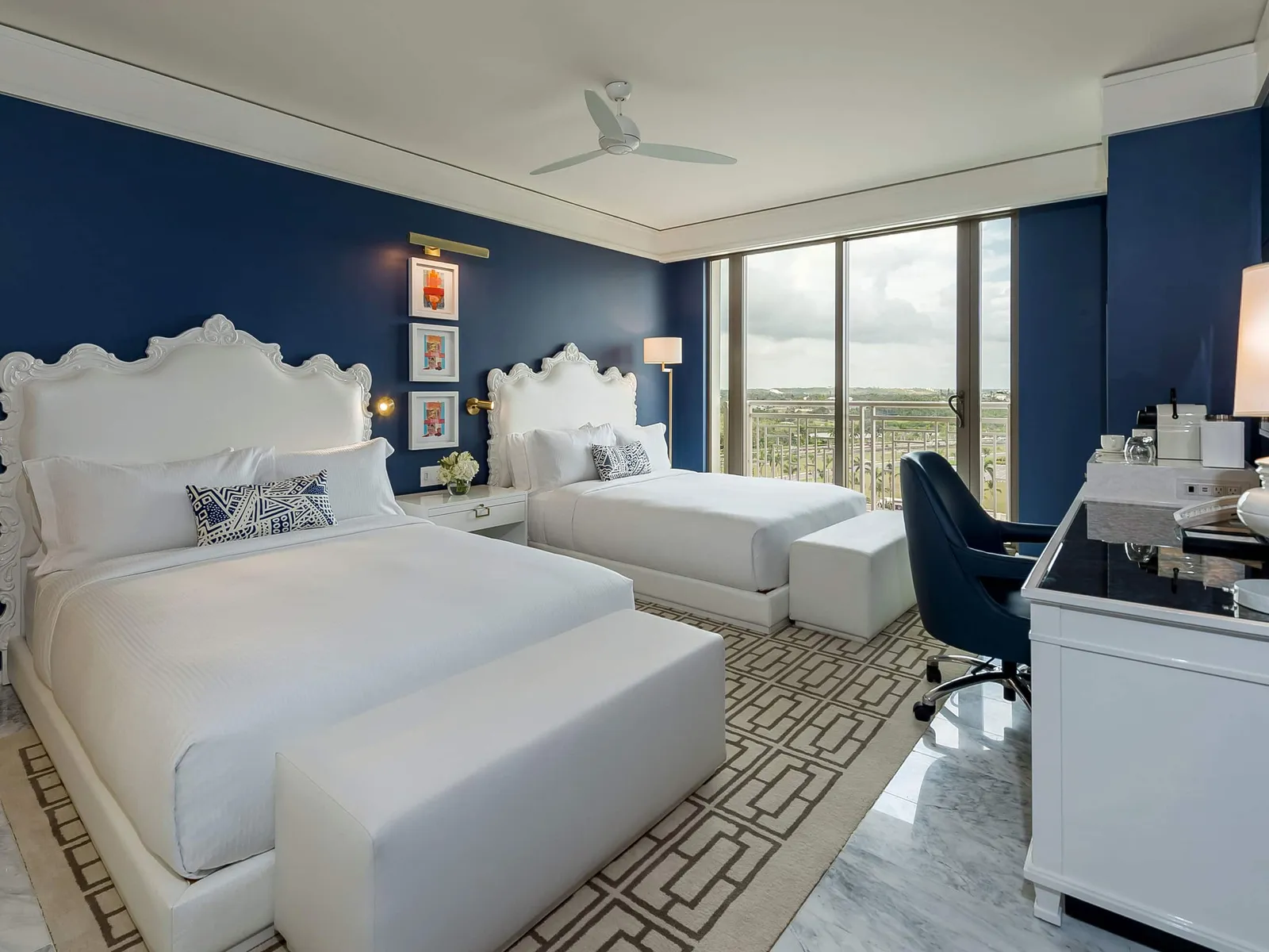 An East Tower Deluxe room with 2 queen beds and white headboards, the key-pattern rug and the desk by the window.