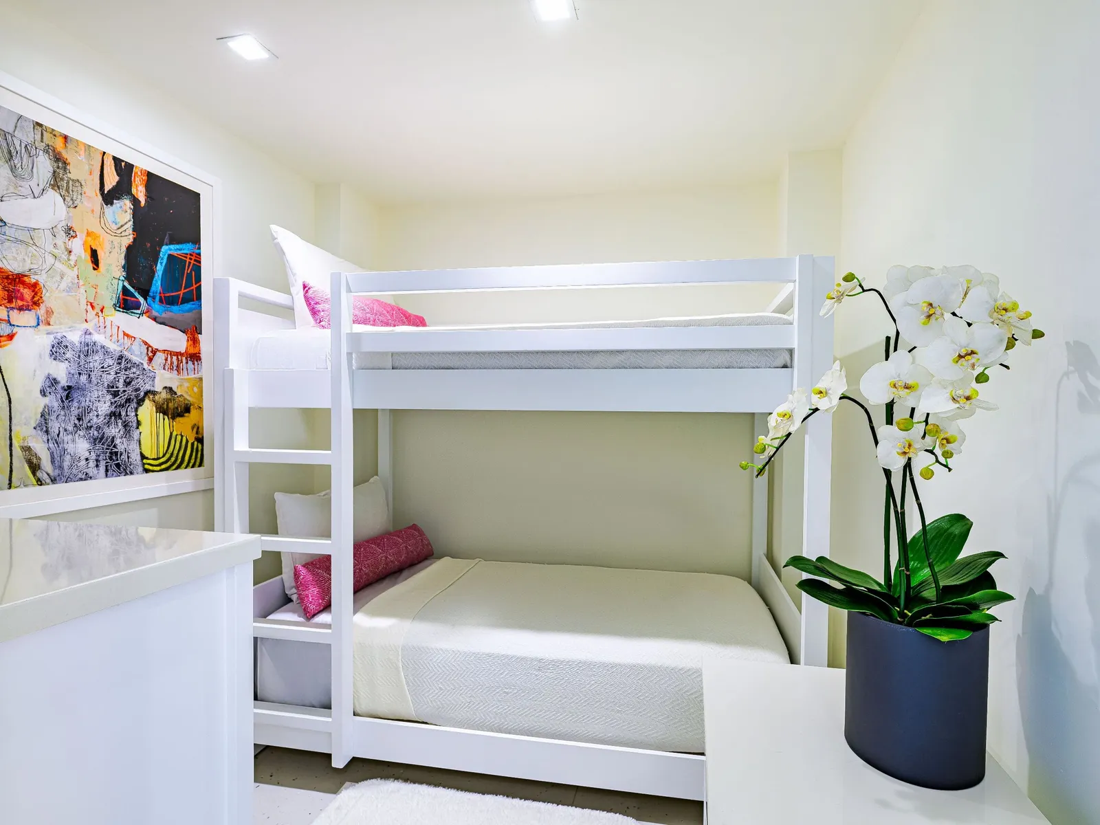 The children’s corner of the Family Suite: a white bunk bed with fuchsia cushions, a colourful painting and a white orchid.